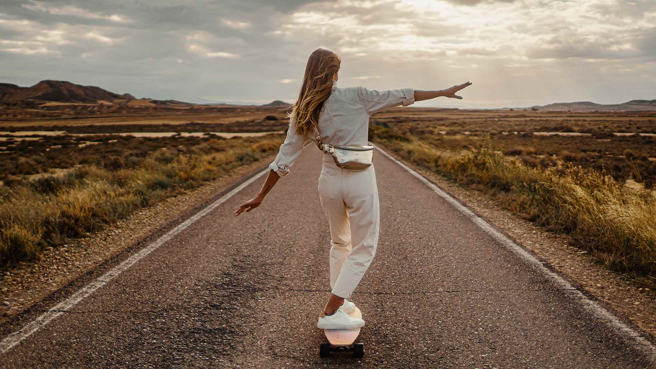 Femme faisant du skate avec un sac banane en cuir doré