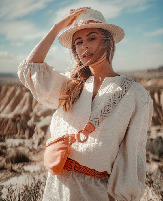Femme dans les dunes portant un chapeau en feutre et un sac banane en corail en veau velours