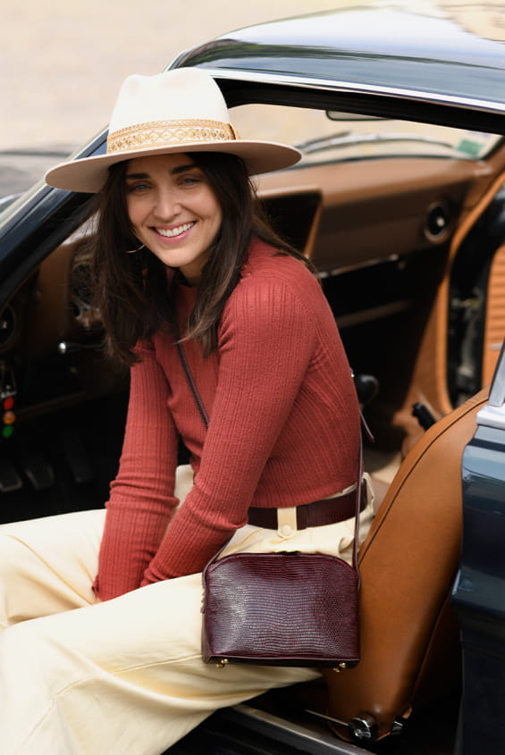 woman sit in a retro car with a handag